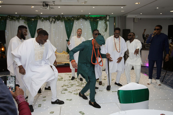 Groom and groomsmen dance on money-covered dancefloor